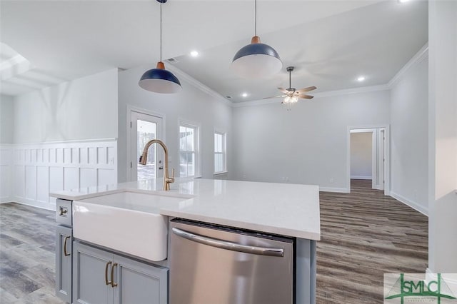 kitchen with crown molding, light countertops, a kitchen island with sink, a sink, and dishwasher