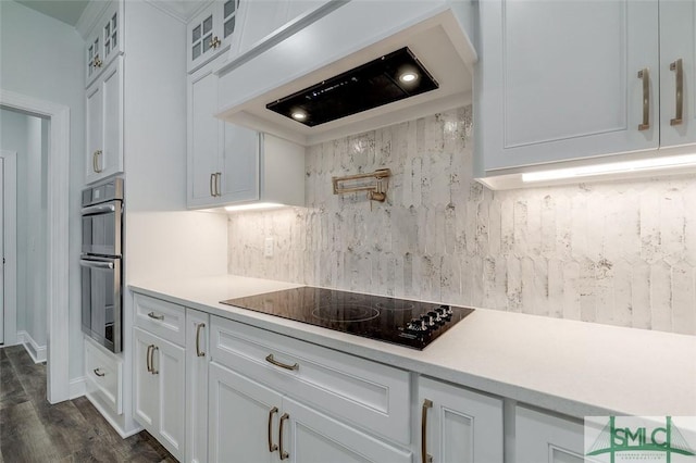 kitchen featuring glass insert cabinets, premium range hood, white cabinetry, and light countertops