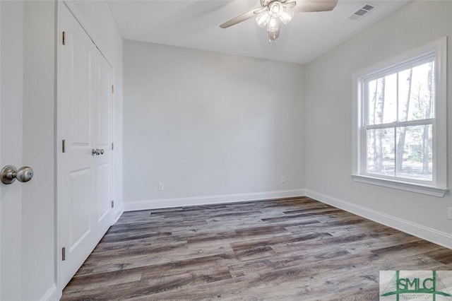 unfurnished room featuring dark wood-style floors, visible vents, ceiling fan, and baseboards