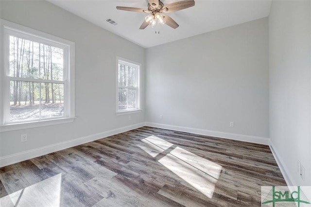 unfurnished room featuring visible vents, wood finished floors, a ceiling fan, and baseboards