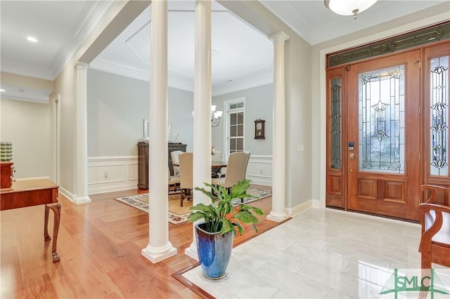 entrance foyer featuring ornamental molding, wainscoting, decorative columns, and a decorative wall