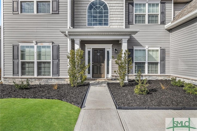 property entrance featuring stone siding and a yard