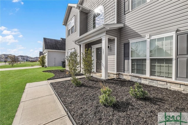 property entrance with stone siding and a lawn