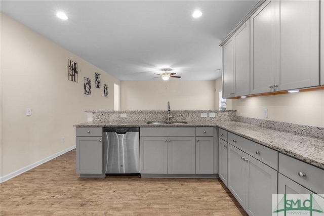 kitchen featuring gray cabinetry, a sink, light stone countertops, dishwasher, and a peninsula