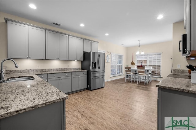 kitchen featuring appliances with stainless steel finishes, a sink, decorative light fixtures, and gray cabinetry