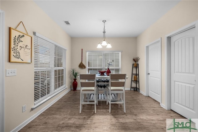 dining area with plenty of natural light, wood finished floors, visible vents, and baseboards