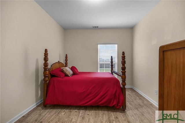 bedroom with light wood finished floors, visible vents, and baseboards