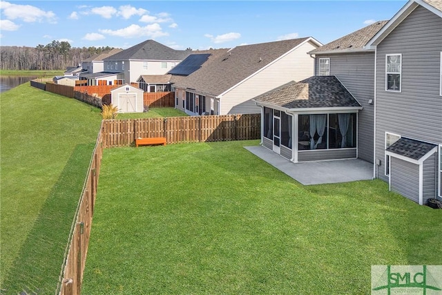 view of yard with a sunroom, a patio area, a fenced backyard, and a shed