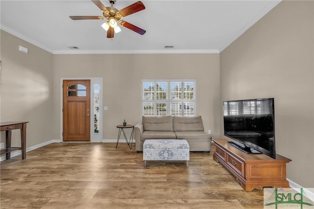 living area with baseboards, visible vents, crown molding, and wood finished floors