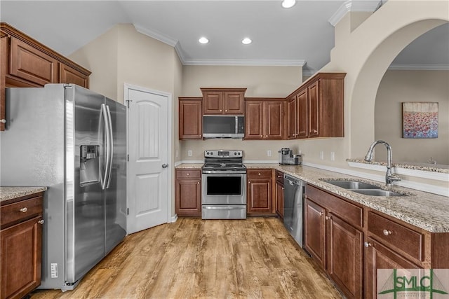 kitchen featuring stainless steel appliances, wood finished floors, a sink, and crown molding