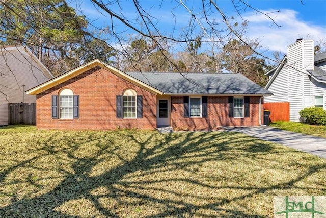 single story home featuring brick siding, fence, a front lawn, and roof with shingles