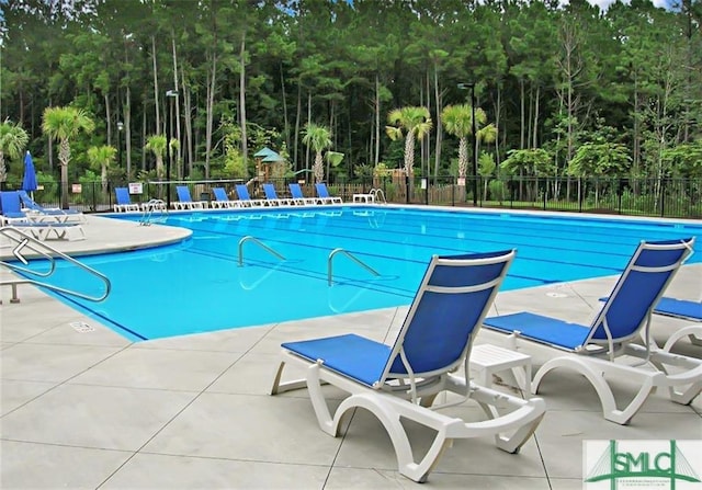 community pool with a patio and fence