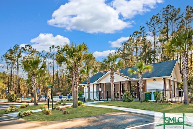 view of front of property featuring a community pool and fence