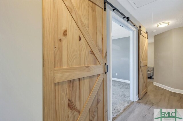 469 Nashview Trl, Allenhurst, GA 31301 - hallway with light wood finished floors, a barn door, and baseboards
