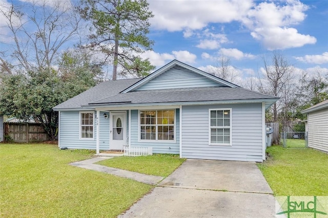 view of front of property with roof with shingles, a front yard, and fence