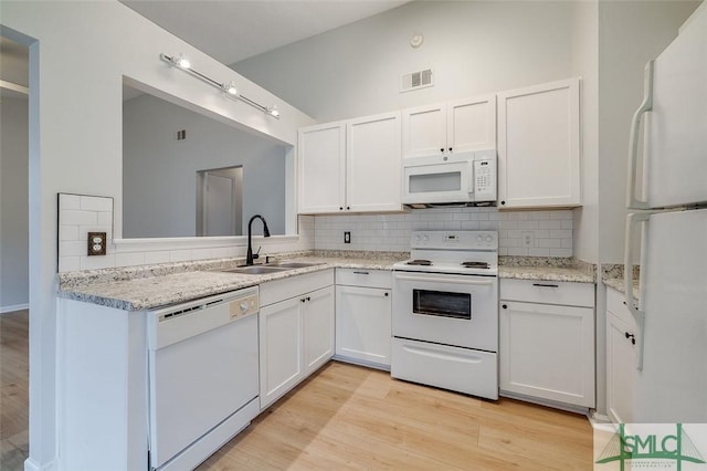 kitchen with white appliances, visible vents, a sink, and white cabinets