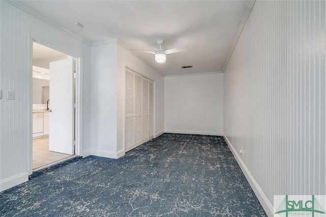 unfurnished bedroom featuring baseboards, visible vents, ceiling fan, ornamental molding, and carpet flooring