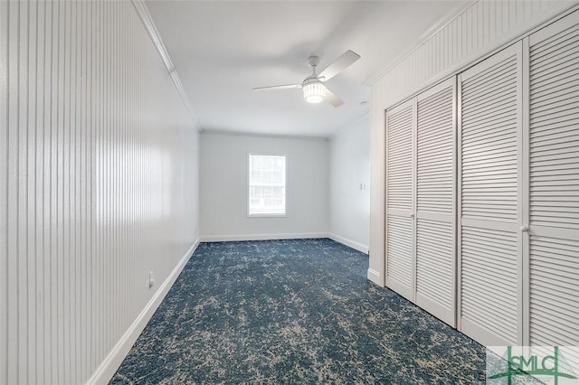 unfurnished bedroom featuring baseboards, ceiling fan, ornamental molding, dark colored carpet, and a closet