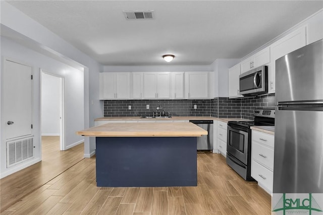 kitchen featuring wooden counters, appliances with stainless steel finishes, visible vents, and white cabinetry