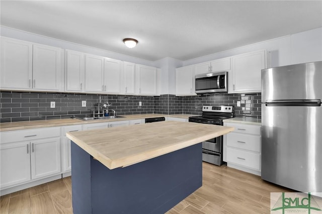 kitchen with a center island, stainless steel appliances, light countertops, white cabinetry, and a sink