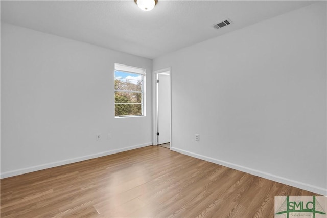 unfurnished room featuring light wood-style flooring, visible vents, and baseboards