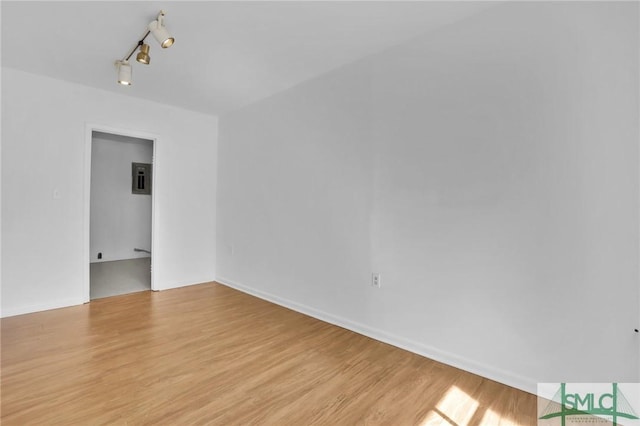 spare room with baseboards, track lighting, and light wood-style floors