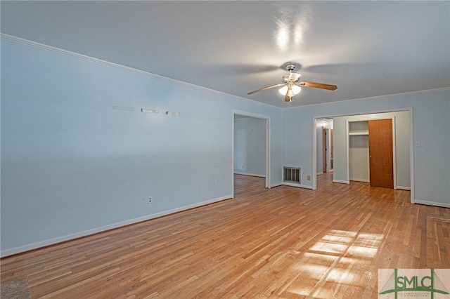 empty room featuring light wood-type flooring, visible vents, crown molding, and baseboards