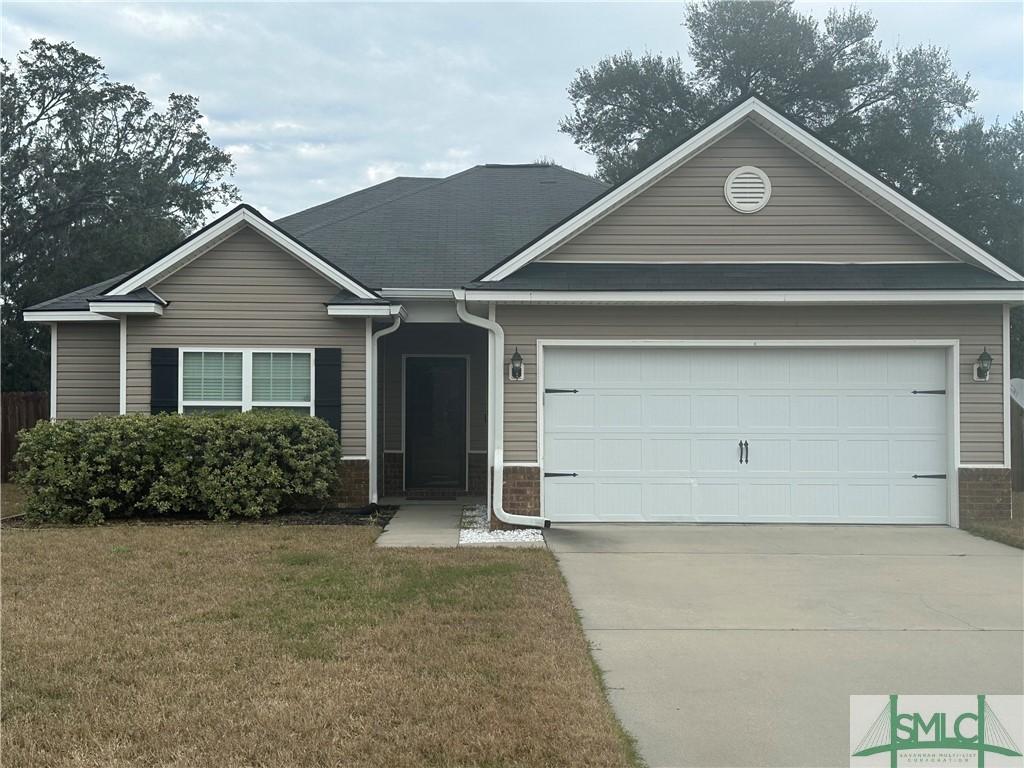 ranch-style house with a front yard, concrete driveway, and an attached garage