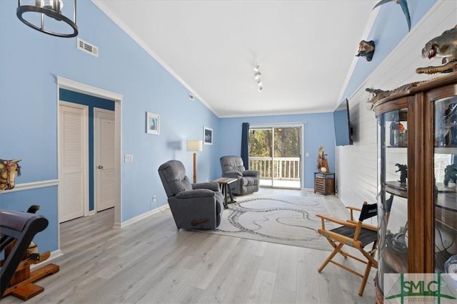 sitting room featuring lofted ceiling, light wood-type flooring, visible vents, and crown molding