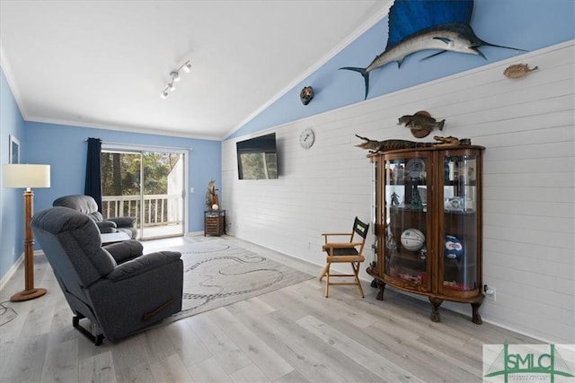 living area with light wood-style flooring, ornamental molding, and vaulted ceiling