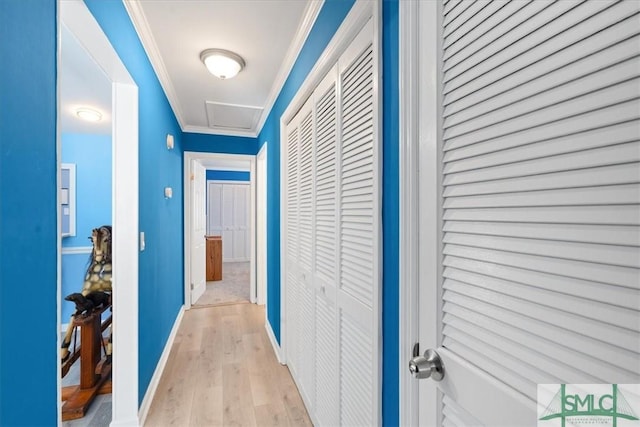 hallway with baseboards, light wood-style floors, attic access, and crown molding