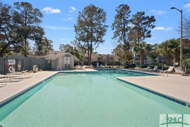 community pool with a patio and fence