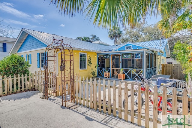 view of front of property featuring a fenced front yard, a sunroom, and metal roof