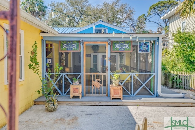 view of outbuilding with a sunroom and fence