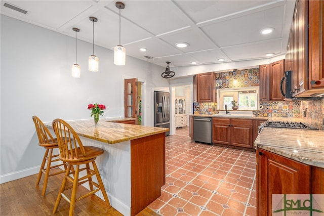 kitchen featuring stainless steel appliances, brown cabinets, a kitchen breakfast bar, and tasteful backsplash