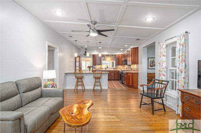 living room with a ceiling fan, recessed lighting, coffered ceiling, and light wood-style flooring