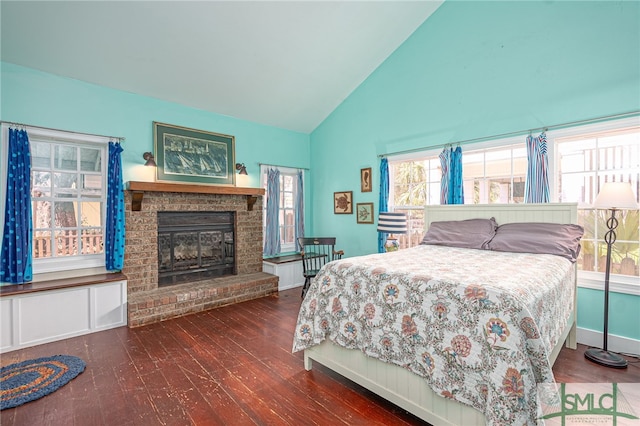 bedroom featuring vaulted ceiling, a brick fireplace, dark wood finished floors, and baseboards