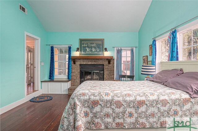 bedroom featuring a fireplace, visible vents, vaulted ceiling, and wood finished floors