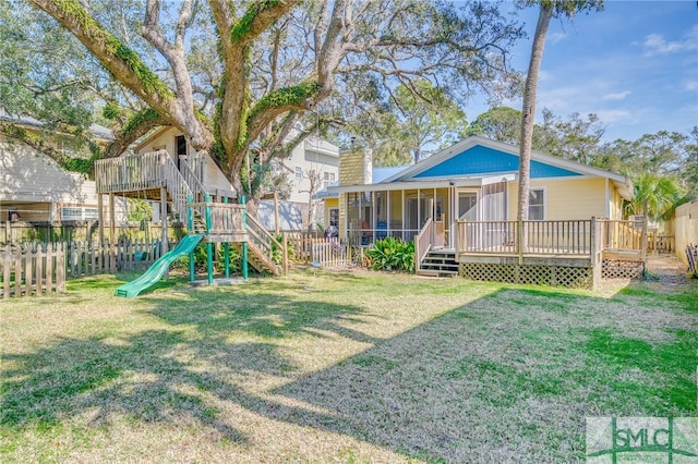 view of playground with a sunroom, a lawn, a fenced backyard, and a wooden deck