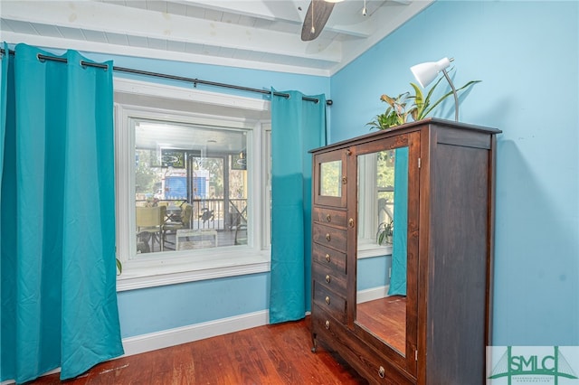 unfurnished bedroom with dark wood-type flooring, beam ceiling, and baseboards