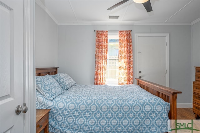 bedroom featuring ceiling fan, visible vents, wood finished floors, and ornamental molding