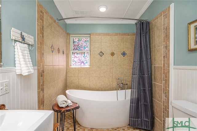 bathroom featuring visible vents, toilet, a wainscoted wall, ornamental molding, and a freestanding bath