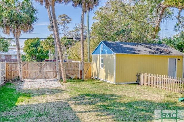 view of yard featuring an outbuilding, a gate, a fenced backyard, and a shed