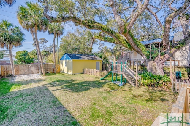 view of playground featuring an outbuilding, a yard, a shed, and a fenced backyard