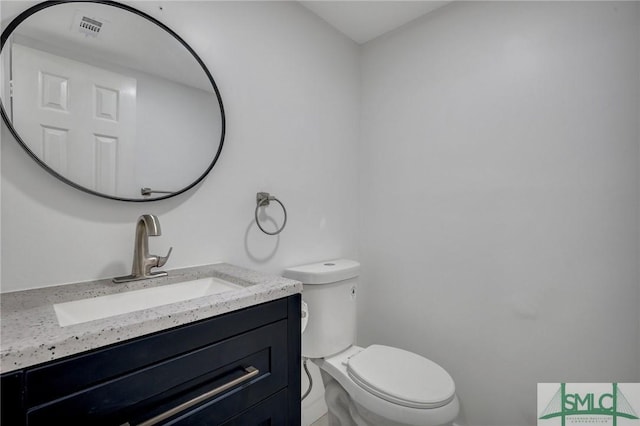 half bath featuring toilet, visible vents, and vanity