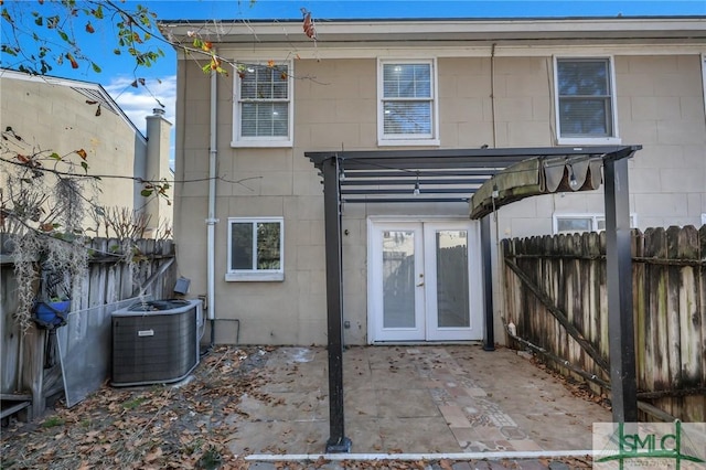 rear view of house featuring central air condition unit, a fenced backyard, concrete block siding, and french doors