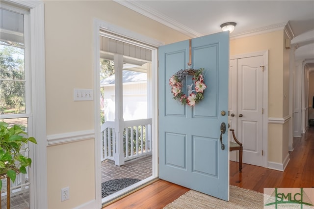 entrance foyer with ornamental molding and wood finished floors