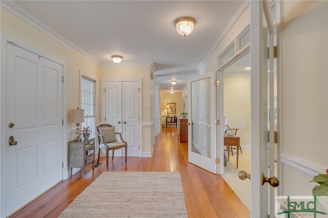 foyer entrance featuring light wood finished floors, ornamental molding, and french doors