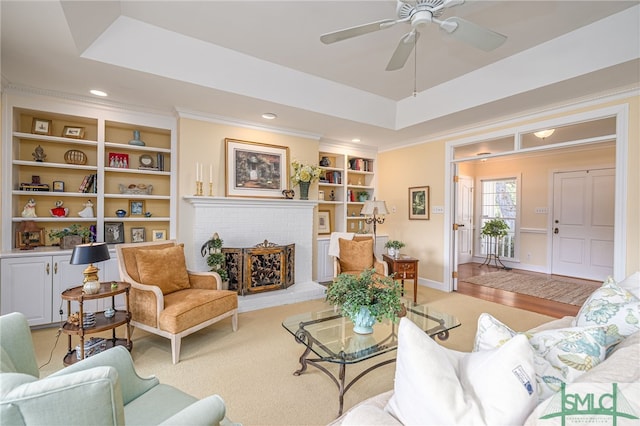 living room with built in features, a raised ceiling, crown molding, and baseboards