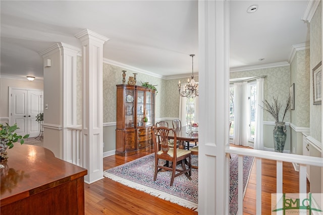 dining space with wallpapered walls, baseboards, ornamental molding, wood finished floors, and an inviting chandelier